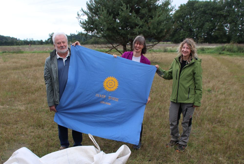 Pressetermin Sand-Strohblume: Britta Walthelm, Klaus-Peter Murawski, Britta Lajoie mit Fahne von Inner Wheel
